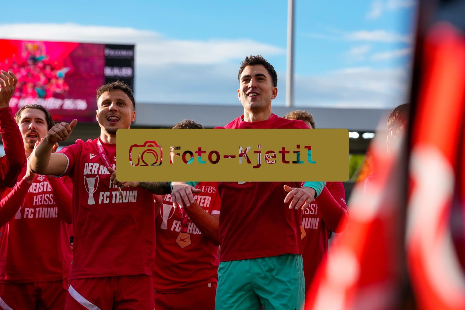 Schweiz: Brack Super League 2025/2026, FC Thun vs BSC Young Boys - Stockhorn Arena, Thun: FC Thun als Schweizer Meister 2026 nach dem letztjährigen Aufstieg in die höchste Schweizer Liga, ist zum ersten mal in der Klubgeschichte Meister.: Nino Ziswiler (Torhüter 1 THU), Dominik Franke (5 THU) mit Marc Gutbub (33 THU) am feiern vor der Fankurve mit dem Pokal